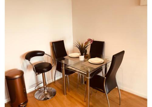 een eetkamer met een glazen tafel en zwarte stoelen bij 3 Bedroom Beautiful Apartment in Manchester