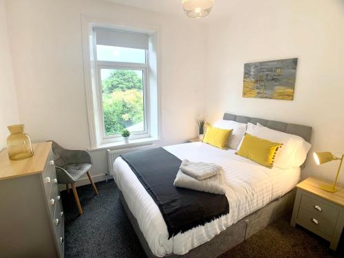 a bedroom with a bed with yellow pillows and a window at CrowTrees in Brighouse