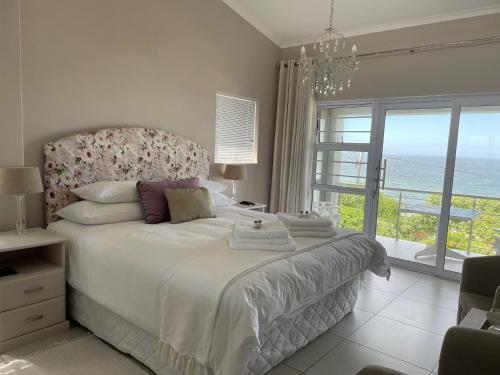 a bedroom with a large bed with a large window at Vermont Hermanus - views, sunny, right on the sea in Hermanus