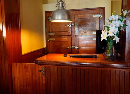 a counter with a vase of flowers and a lamp at Hotel Danae in Piriápolis