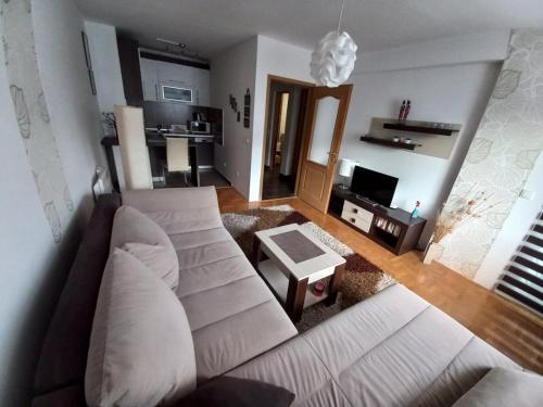 a living room with a white couch and a tv at Apartman Pivasevic in Sarajevo