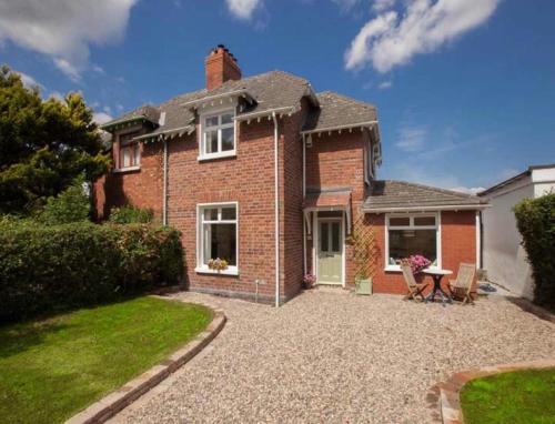 a brick house with a table in the front yard at Stylish 2BR Cottage Garden & Parking 5 mins to Titanic in Belfast