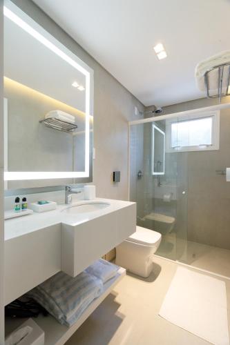 a bathroom with a sink and a toilet and a mirror at Villa d'Ozio Hotel e Cucina in Itajaí