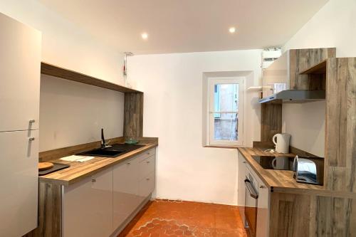 une cuisine avec des armoires blanches et un comptoir en bois dans l'établissement Atypical 1 bedroom appartment in rue Fourmillière, à Antibes