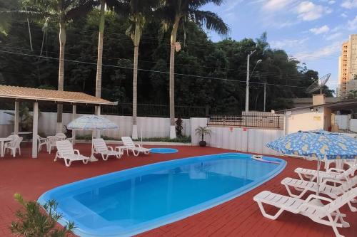 una piscina con sillas blancas y sombrillas junto a en Kit 6 Residencial Diego Marcelo, en Itapema