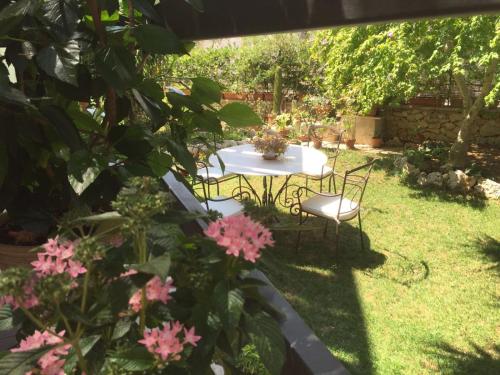 a table and chairs in a garden with pink flowers at Casa Noemi b&b in Uggiano la Chiesa