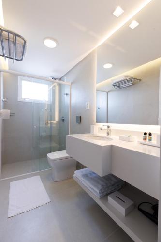 a bathroom with a sink and a shower and a toilet at Villa d'Ozio Hotel e Cucina in Itajaí