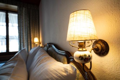 a lamp sitting next to a bed in a bedroom at La Fleur de Lys in Gruyères
