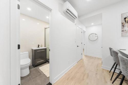 a white bathroom with a toilet and a sink at Stonewall Suites in Montréal