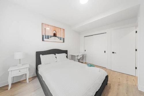 a white bedroom with a bed and a white cabinet at Stonewall Suites in Montréal