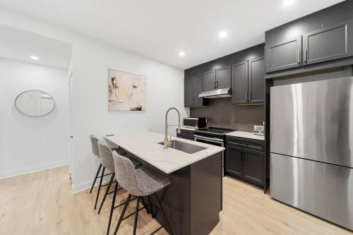 a kitchen with black cabinets and a stainless steel refrigerator at Stonewall Suites in Montréal