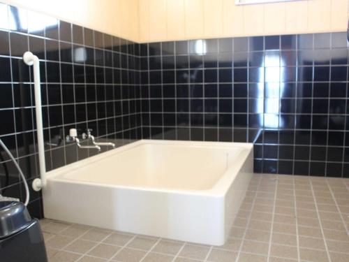 een badkamer met een bad en zwarte tegels bij Yugaku Resort Kimukura - Vacation STAY 89356v in Tokunoshima