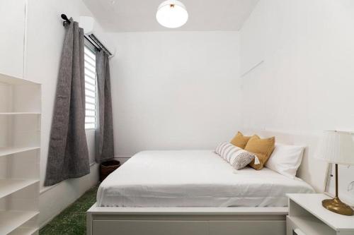 a white bedroom with a bed and a window at Digital Nomad San Agustin Apartments in San Juan