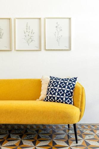 a yellow couch in a living room with pictures on the wall at Digital Nomad San Agustin Apartments in San Juan