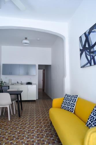 a living room with a yellow couch and a kitchen at Digital Nomad San Agustin Apartments in San Juan