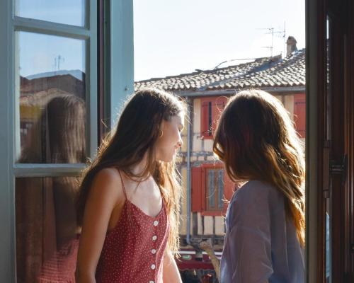 two girls are looking out of a window at La Maison des Consuls in Mirepoix