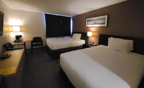 a hotel room with two beds and a desk at Roadking Inns Motel in Calgary