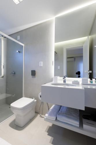 a white bathroom with a toilet and a sink at Villa d'Ozio Hotel e Cucina in Itajaí