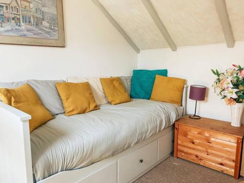 a couch with yellow and blue pillows on it at Riverside loft apartment in Newport