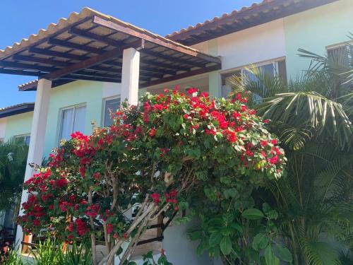a house with red flowers on the side of it at Condomínio Lírios Paraíso de Paz e Beleza in Mata de Sao Joao