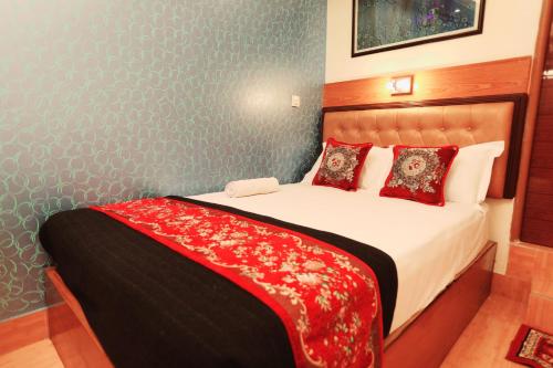 Hotel Shalimar Motijheel - Centre of City في داكا: غرفة نوم بسرير كبير عليها شراشف ومخدات حمراء