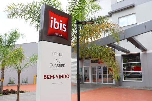 um sinal em frente a um edifício com um sinal de ibm em Ibis Guaxupe em Guaxupé