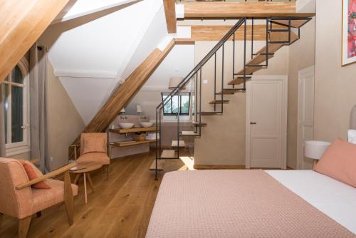 a room with a staircase and a bed and chairs at La Maison du Môle in Aigues-Mortes