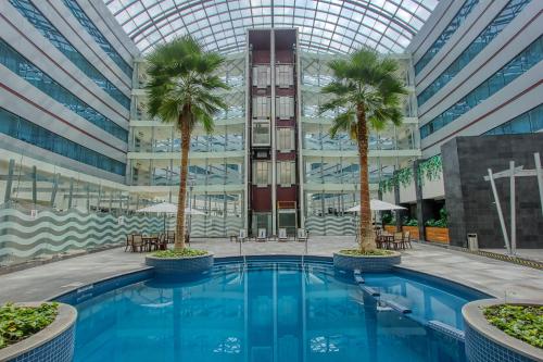a pool in front of a building with palm trees at Crowne Plaza Leon by IHG in León