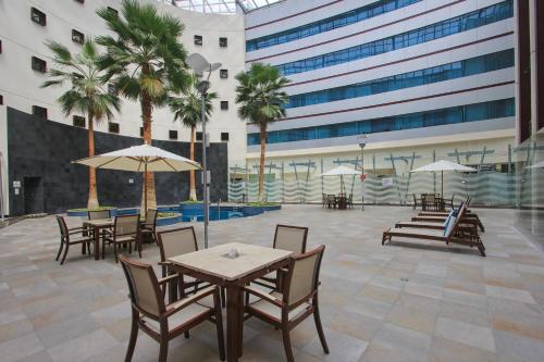 a patio with tables and chairs and palm trees at Crowne Plaza Leon by IHG in León