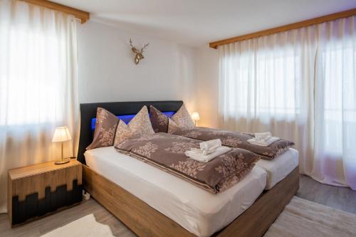 - une chambre dotée d'un grand lit avec des couvertures et des oreillers bruns dans l'établissement Agrimonia - möbilierte Ferienwohnung mit Balkon, à Davos