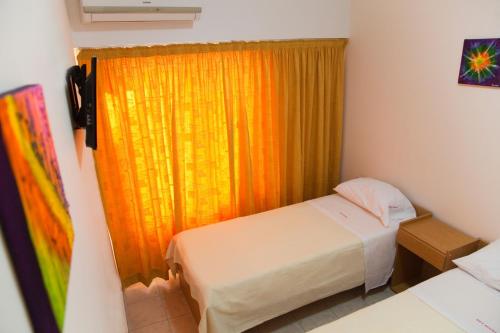 a bedroom with a bed and a window with an orange curtain at Bet Hotel Buenos Aires in Buenos Aires