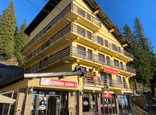 a yellow building with people standing on the balcony at Hotel Restaurant Alessia in Ranca