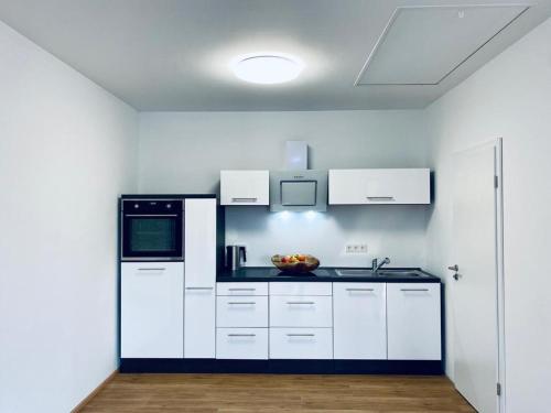 a kitchen with white cabinets and a bowl of fruit on the counter at Ferienwohnungen Nalbach Bierbach in Nalbach