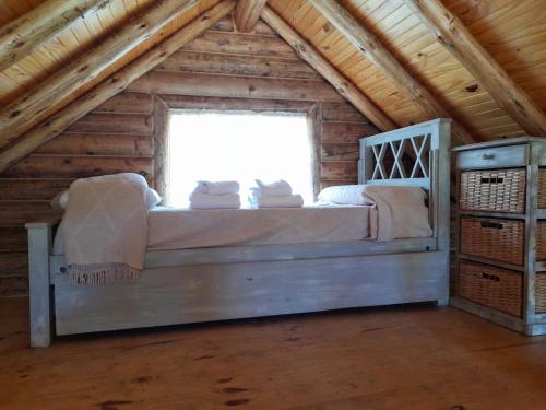 a bed in a log cabin with a window at La Escondida in Tunuyán