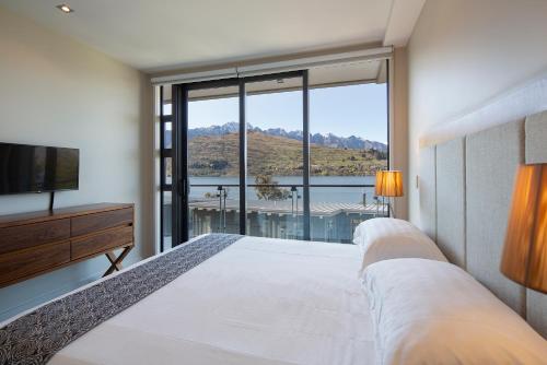 a bedroom with two beds and a large window at The Rees Hotel & Luxury Apartments in Queenstown