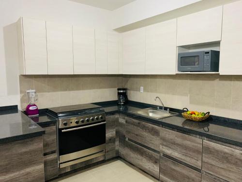 a kitchen with white cabinets and a stove and a sink at Franks House "Shared House" Apartment in Cancún