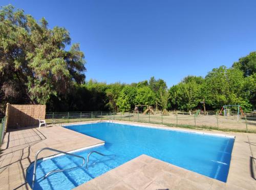 a swimming pool with a playground in the background at Casa de Adobe Remanso del Espíritu in Isla de Maipo