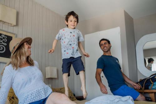 a young boy jumping on a bed with two adults at Tangoinn Club Hotel in San Carlos de Bariloche