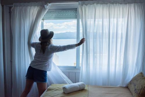 a woman in a hat looking out of a window at Tangoinn Club Hotel in San Carlos de Bariloche