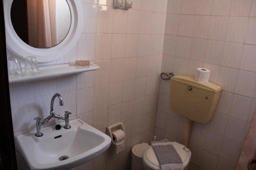 a bathroom with a sink and a toilet and a mirror at Hotel Stavris in Khóra Sfakíon