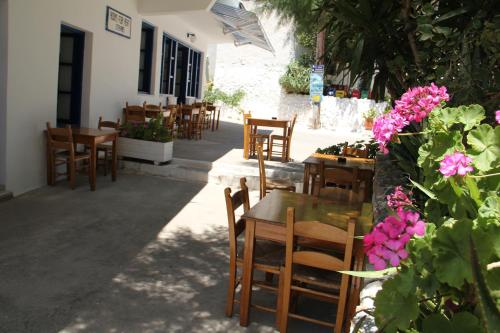 a restaurant with tables and chairs and pink flowers at Hotel Stavris in Khóra Sfakíon