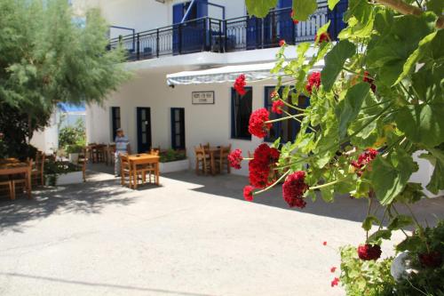 a building with red flowers and tables and chairs at Hotel Stavris in Khóra Sfakíon