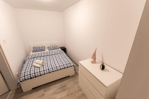 um pequeno quarto branco com uma cama e uma cómoda em Apartament Krakowska em Czestochowa