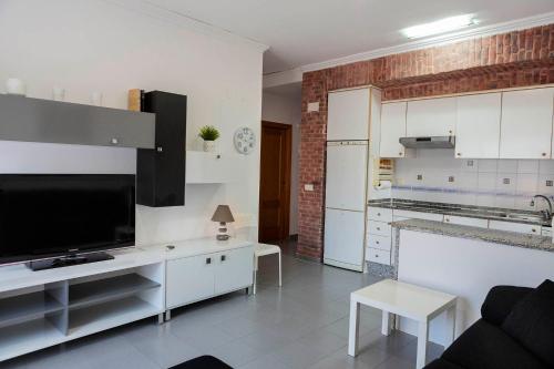 a living room with a television and a white kitchen at Apartamento planta baja en playa Canet de Berenguer in Canet de Berenguer
