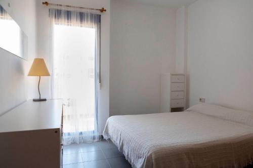 a white bedroom with a bed and a window at Apartamento planta baja en playa Canet de Berenguer in Canet de Berenguer