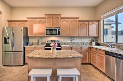 a kitchen with wooden cabinets and a kitchen island with two stools at Pool and Game Room Home in Goodyear Near Golfing in Liberty