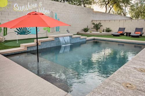 a swimming pool with a red umbrella and a fountain at Pool and Game Room Home in Goodyear Near Golfing in Liberty