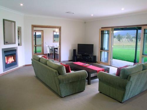 a living room with two couches and a fireplace at Kinsale Cottage in Pokolbin