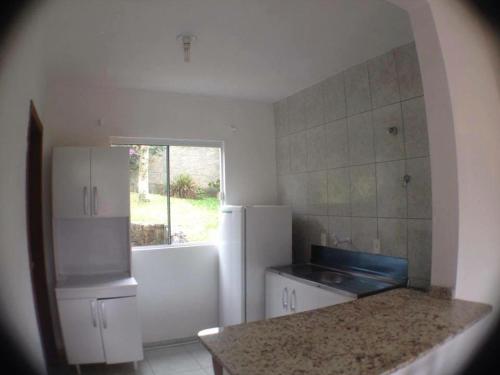 a kitchen with a white refrigerator and a sink at Pousada Dunas Da Joaquina in Florianópolis