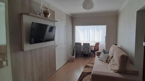 a living room with a couch and a television on a wall at Apartamento Inteiro jardim Iririú in Joinville